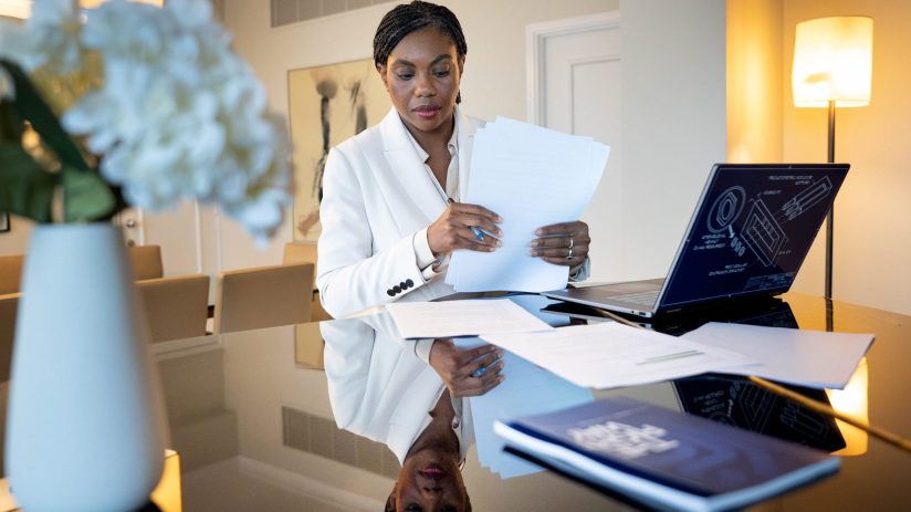 Kemi Badenoch, Secretary of State for Business and Trade, preparing for a conference speech, reviewing documents at a desk.