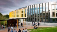 Bradfield Centre Unit 184 at Cambridge Science Park, a modern building with yellow accents and people gathering outside.