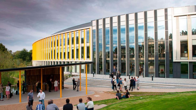 Bradfield Centre Unit 184 at Cambridge Science Park, a modern building with yellow accents and people gathering outside.
