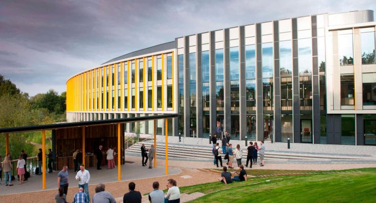 Bradfield Centre Unit 184 at Cambridge Science Park, a modern building with yellow accents and people gathering outside.