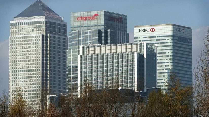 Canary Wharf financial district skyline with HSBC and Citigroup buildings visible above trees.