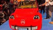 Red Citroen CV2 concept car on display at the Paris Motor Show, surrounded by attendees.