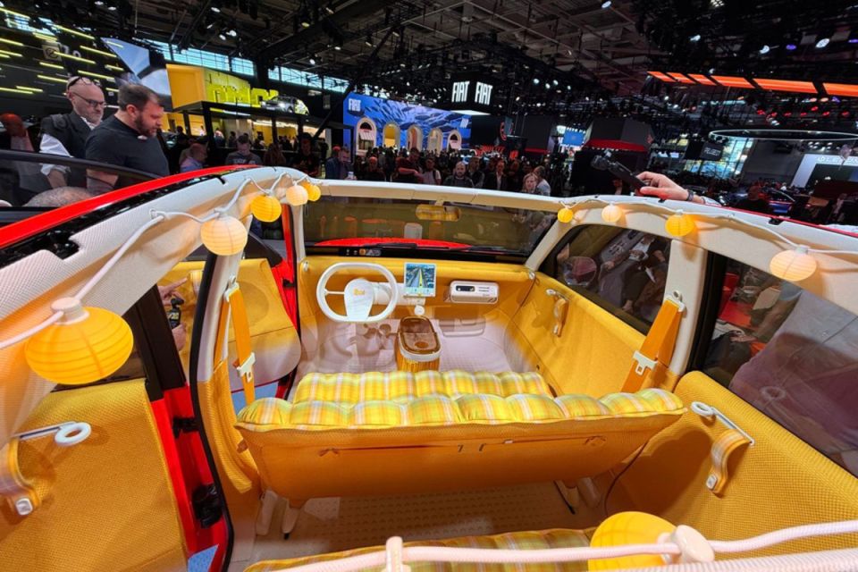 Citroen Oli electric concept car interior at an auto show, featuring yellow plaid seats, white steering wheel, and string ...