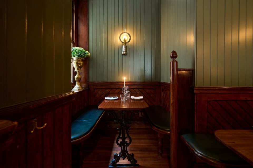 Cozy booth at Simpsons Tavern, Cornhill, London, with dark wood paneling, green walls, and a lit candle.