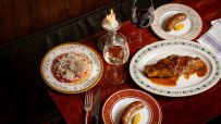 Fine dining experience with various dishes, wine, and a lit candle on a dark wooden table at Cloth Cornhill.
