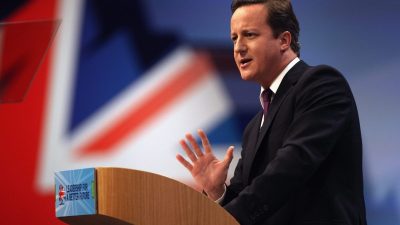 David Cameron speaking at a podium, Union Jack flag backdrop, Leadership for a Better Future visible.