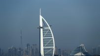 Dubai skyline with Burj Al Arab and Jumeirah Beach Hotel, Burj Khalifa in background over blue water.