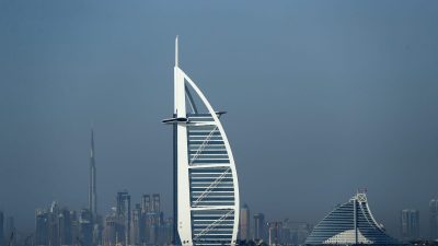 Dubai skyline with Burj Al Arab and Jumeirah Beach Hotel, Burj Khalifa in background over blue water.