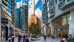 Electric Boulevard at Battersea Power Station, with modern buildings, shops like Zara, and pedestrians.