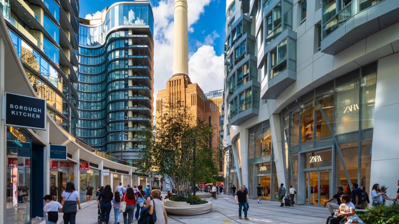 Electric Boulevard at Battersea Power Station, with modern buildings, shops like Zara, and pedestrians.