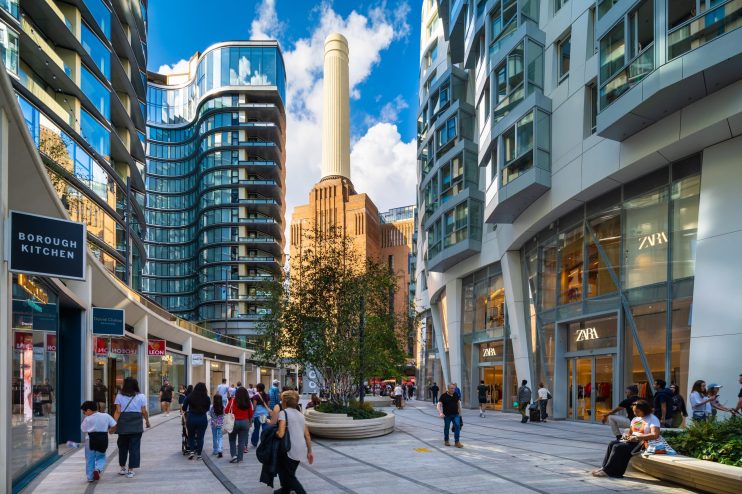 Electric Boulevard at Battersea Power Station, with modern buildings, shops like Zara, and pedestrians.