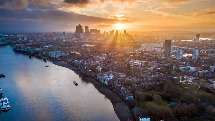 Aerial view of Londons financial district, Canary Wharf, at sunset with the River Thames in the foreground