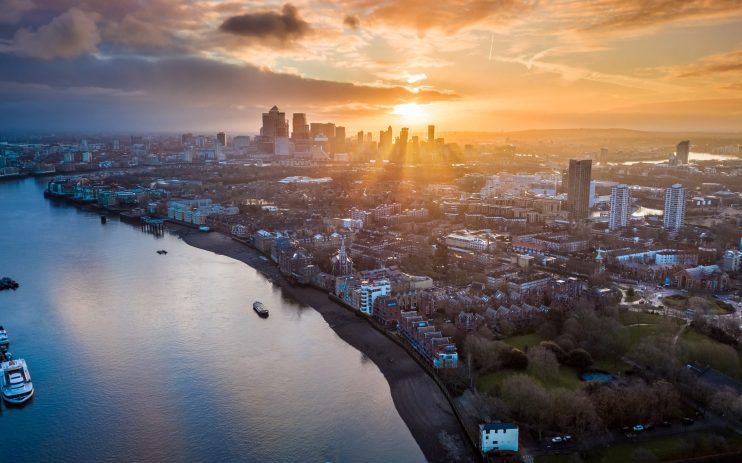 Aerial view of Londons financial district, Canary Wharf, at sunset with the River Thames in the foreground