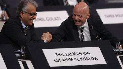 Gianni Infantino shaking hands with Sheikh Salman bin Ebrahim Al Khalifa at a formal event, both smiling.