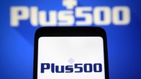 Plus500 logo displayed on a smartphone screen, with a larger, blurred Plus500 logo in the background