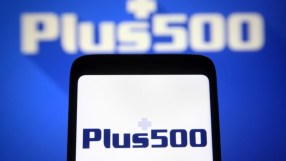Plus500 logo displayed on a smartphone screen, with a larger, blurred Plus500 logo in the background