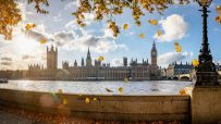 Autumn leaves falling over the River Thames with the Houses of Parliament and Big Ben in London.