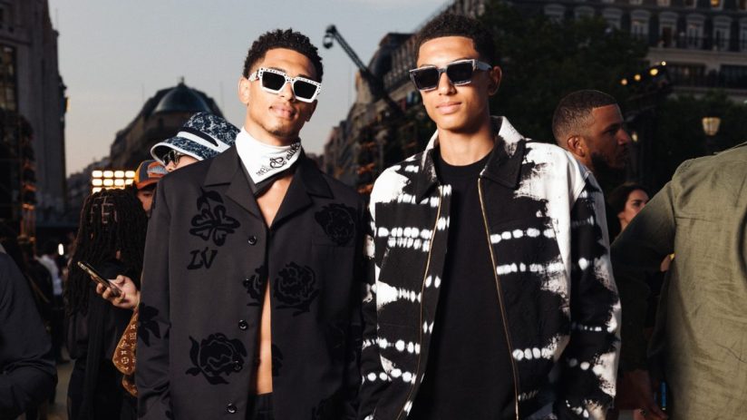 Two young men in stylish black and white streetwear, one with a floral shirt and the other in tie-dye.