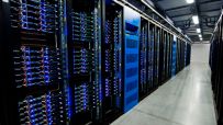 Rows of large server racks with blue lights and cables in a data center aisle