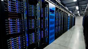 Rows of large server racks with blue lights and cables in a data center aisle