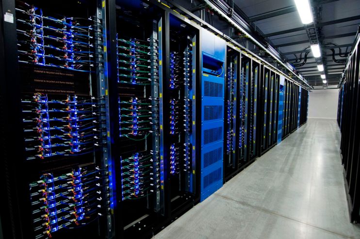Rows of large server racks with blue lights and cables in a data center aisle