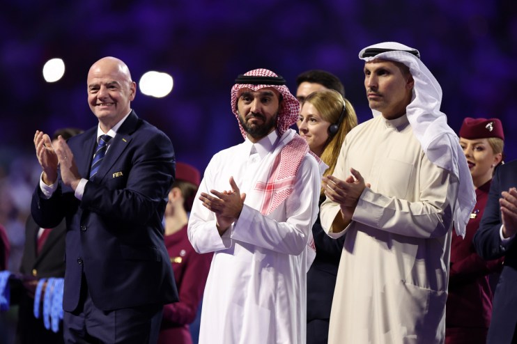 Gianni Infantino applauds alongside two men in traditional Arab attire at an event.