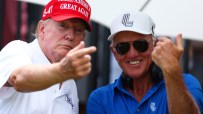 Donald Trump in a red MAGA hat pointing, next to Greg Norman in sunglasses and a white cap, smiling.
