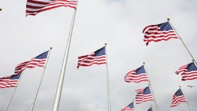 Multiple American flags waving against a cloudy sky, symbolizing patriotism and national identity