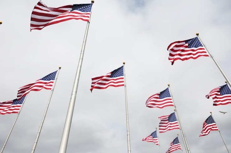 Multiple American flags waving against a cloudy sky, symbolizing patriotism and national identity