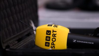 Yellow BBC Sport microphone with a Sennheiser logo, resting in a black padded case.