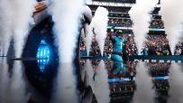 NFL player Travis Etienne Jr. of the Jacksonville Jaguars emerges from a smoky tunnel onto the field, arms raised, with fa...