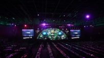 Empty arena seating rows face a stage with Sky Sports and Paddy Power branding, ready for a darts event.