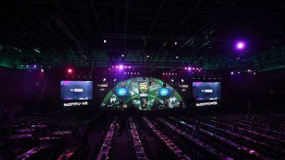 Empty arena seating rows face a stage with Sky Sports and Paddy Power branding, ready for a darts event.