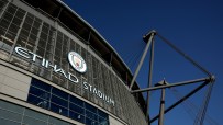Exterior view of Etihad Stadium with Manchester City FC logo against a clear blue sky