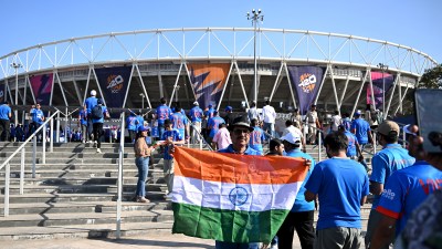 Cricket fans with an Indian flag entering a stadium, ICC T20 World Cup banners visible in the background