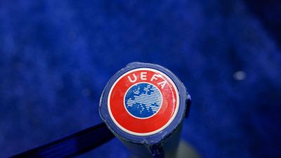 Close-up of a UEFA logo on a blue background, featuring the red circle, blue map of Europe, and white text.