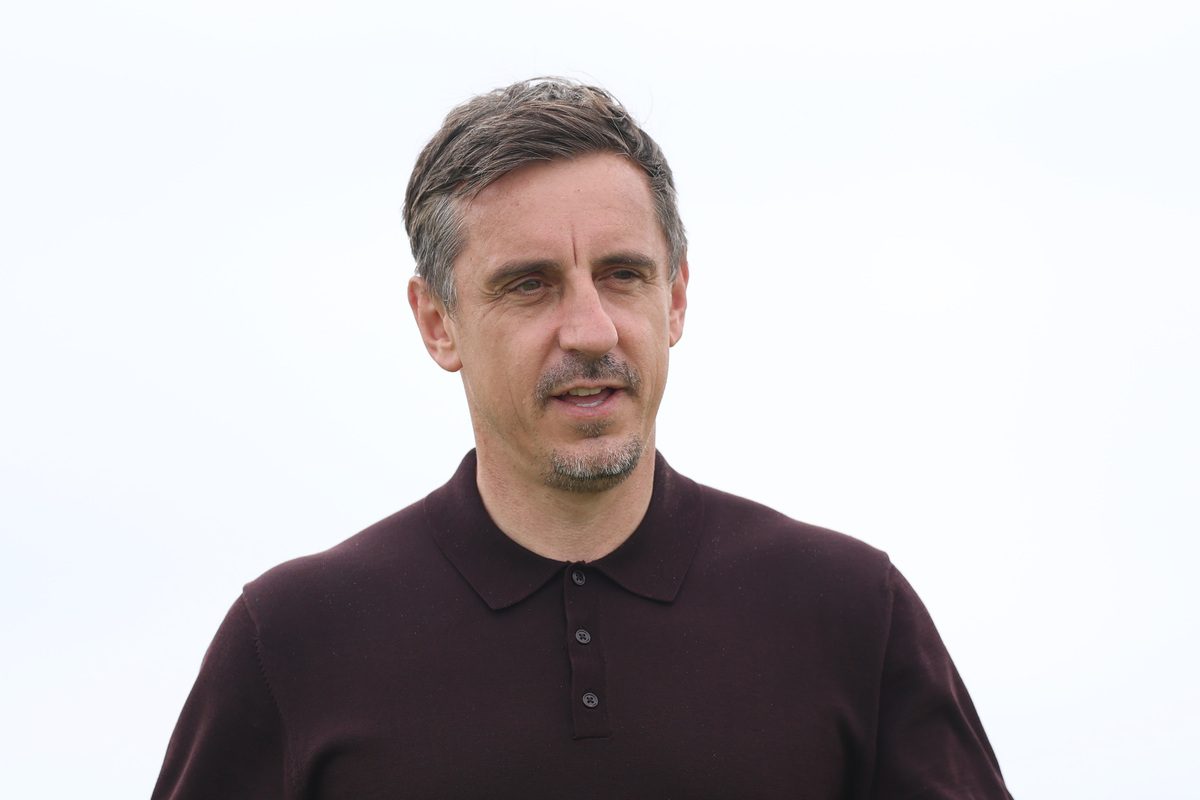 Gary Neville in a dark polo shirt, looking slightly to the right, against a clear sky