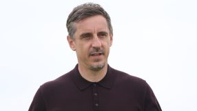 Gary Neville in a dark polo shirt, looking slightly to the right, against a clear sky.
