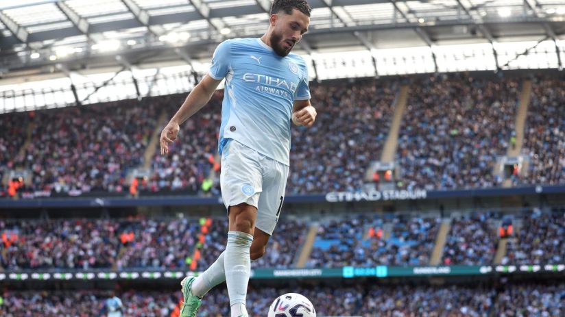 Manchester City player in light blue kit with soccer ball on field during game