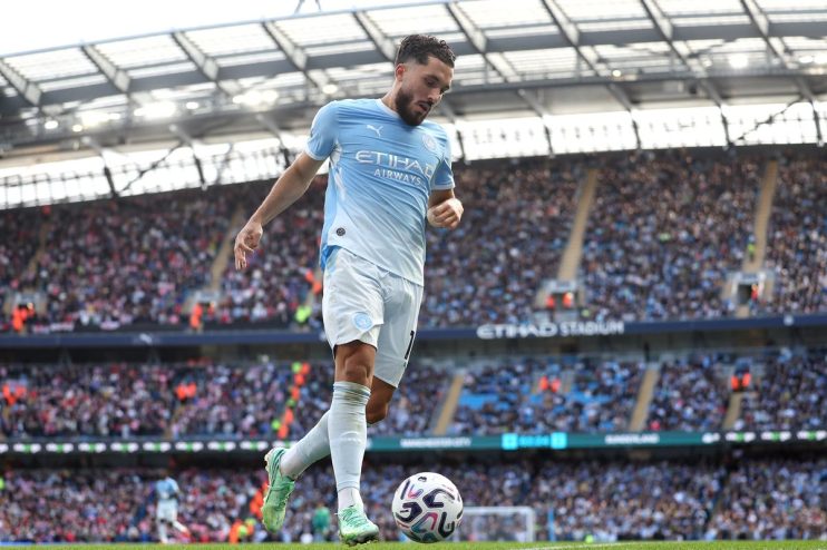 Manchester City player in light blue kit with soccer ball on field during game