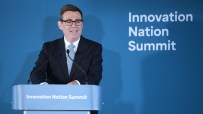 Man in suit and glasses speaking at a podium with Innovation Nation Summit branding