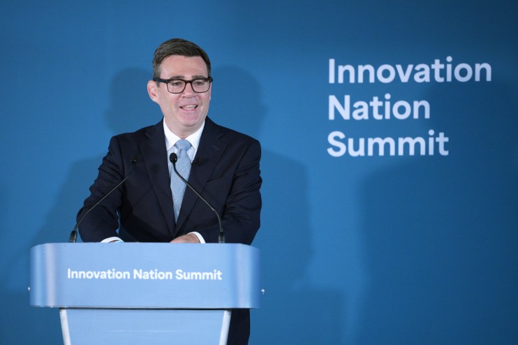 Man in suit and glasses speaking at a podium with Innovation Nation Summit branding