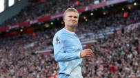 Erling Haaland in Manchester City kit on a football pitch, fans in background