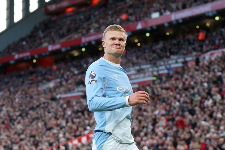 Erling Haaland in Manchester City kit on a football pitch, fans in background
