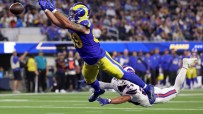Rams player in blue and yellow uniform leaps to catch a football over a Bills player on the ground