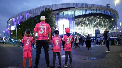 Family in matching Kinsky 31 jerseys standing outside a modern stadium lit with purple lights at dusk.