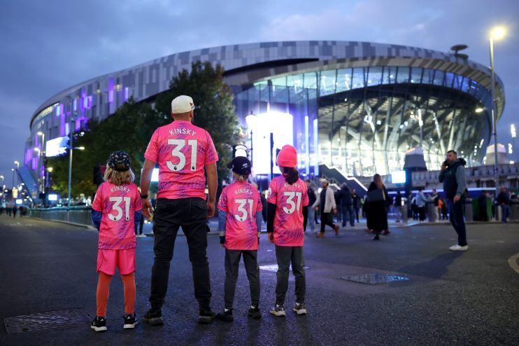 Family in matching Kinsky 31 jerseys standing outside a modern stadium lit with purple lights at dusk.