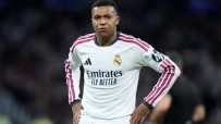 Rodrygo Goes in Real Madrid white and maroon kit, hands on hips, on the pitch.
