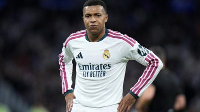 Rodrygo Goes in Real Madrid white and maroon kit, hands on hips, on the pitch.