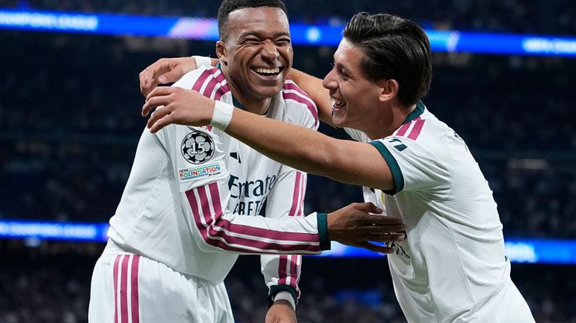 Kylian Mbapp&eacute; in a white jersey with number 10, celebrating with a teammate on a soccer field.